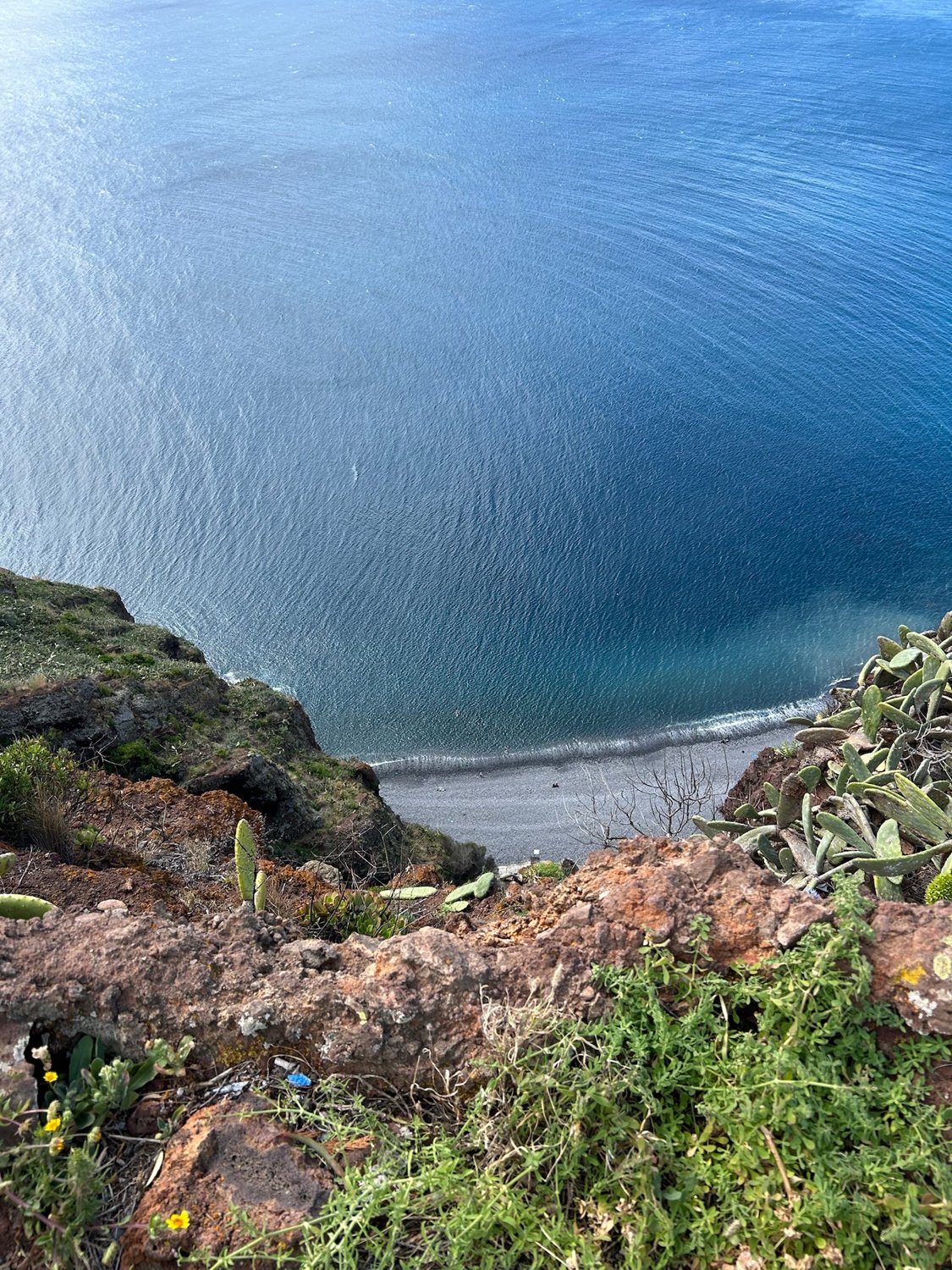 A hidden cove seen from a cliff, deep blue ocean water below